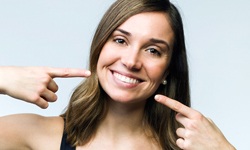 woman pointing to an attractive smile from her cosmetic dentist
