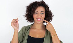Woman pointing at her teeth while holding a clear aligner