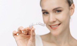 Smiling woman holding a clear aligner