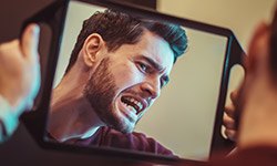 Man looking at his tooth in mirror