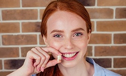 young woman holding tooth after extraction