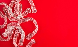 several clear aligners in front of a red background 