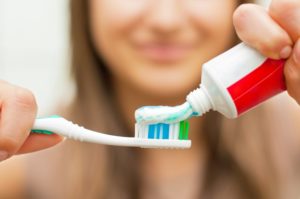 person putting toothpaste on toothbrush