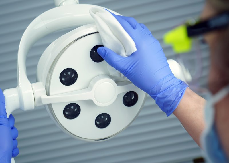 an emergency dentist in Middleburg Heights cleaning the overhead light before the next patient arrives