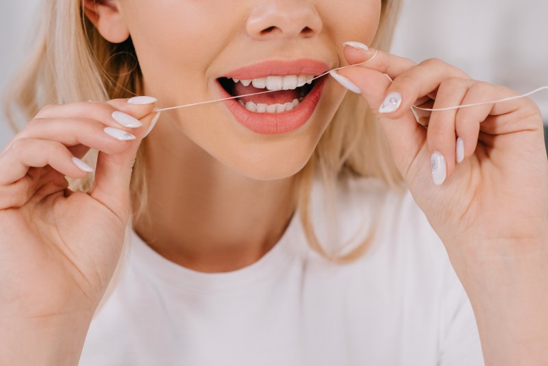 young woman flossing teeth