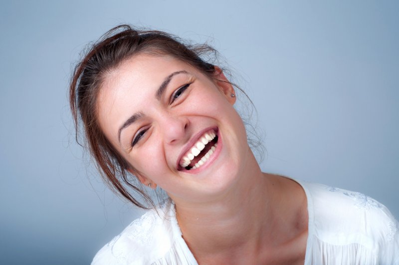 Woman tilting her head to the side and laughing with whitened teeth
