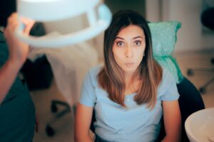 Concerned-looking patient sitting in dentist’s chair wide-eyed.
